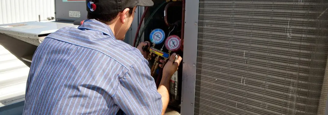 HVAC technician servicing a condenser unit in Long Branch
