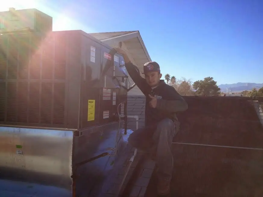 HVAC technician performing Air Duct Cleaning on a rooftop unit in Long Branch